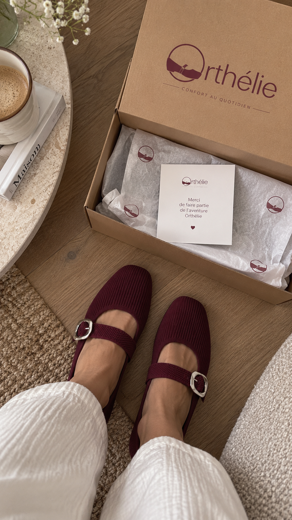 Ballerines Orthélie bordeaux portées, à côté du coffret